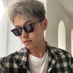 Classic small square black sunglasses with metal rivets worn by a model in a bright studio