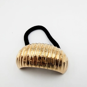 Detail of golden bamboo texture metal hair cuff on a high elasticity black ponytail holder