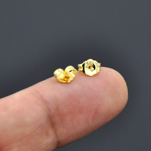 18K gold-plated 925 silver butterfly earring backs shown on fingertip for size scale