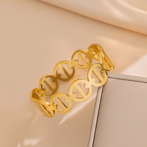 Elegante bracciale rigido in acciaio al titanio dorato con motivi geometrici