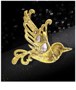 Macro view of bird brooch reverse side with golden metal alloy pin and gray gemstone