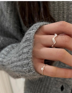Close-up of minimalist S925 silver wave ring and small freshwater pearl ring for women