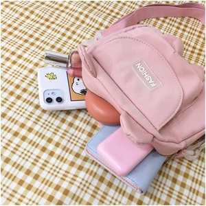 Pink nylon crossbody bag interior showing phone, perfume, and wallet storage capacity