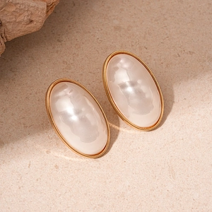 Vintage oval pearl earrings with gold plating and French retro style on textured background