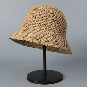 Detail of handcrafted khaki straw bucket hat on stand showing tight weave and texture