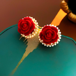 Détail de boucles d'oreilles roses floquées rouges avec perles sur écrin vert foncé