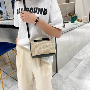 Detail of straw woven crossbody bag featuring black PU leather trim and metal lock closure
