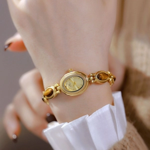 Close-up of gold vintage lady watch with tiger eye stone chain on female wrist