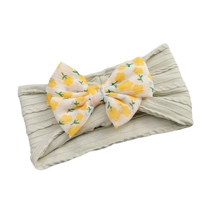 Green ribbed baby headband with a large yellow floral print bow on a clean background