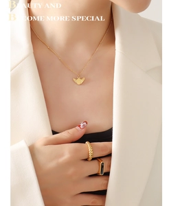 Chic gold-plated wing pendant necklace and ring set styled on a model in a white blazer