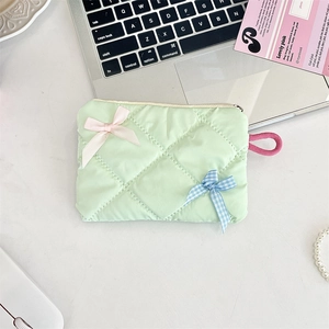 Quilted mint green makeup bag with pink satin and blue checkered bow details on desk