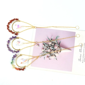 Detailed suncatcher with gold metal moon and natural chakra stones hanging over a white background