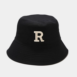 Détail d'un chapeau bob noir avec une broderie 3D de la lettre R blanche en gros plan