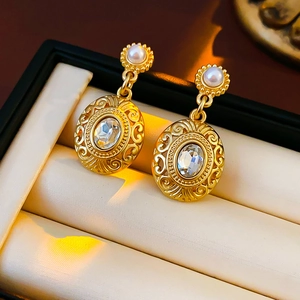 Detail of vintage gold oval earrings featuring central crystal and pearl in jewelry box