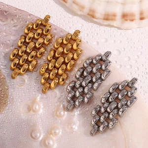 Detailed macro view of 18K gold and silver strap chain earrings on a pearly shell surface