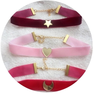 Velvet chokers with gold star, heart, and crescent moon pendants on white faux fur