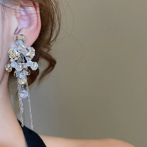 Detailed view of silver tassel earrings with sparkling zircon flowers on a model