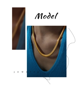Close-up of golden wide snake chain necklace worn on a model with blue knitwear