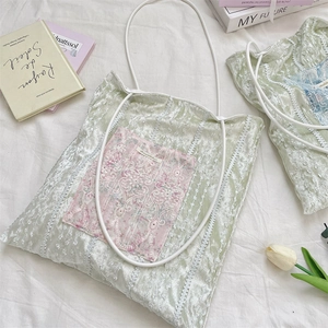 Detailed texture of green canvas tote with pink lace embroidery and floral accents
