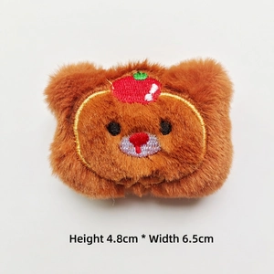 Close-up of small plush bear with apple hat accessory, measuring 4.8cm high and 6.5cm wide