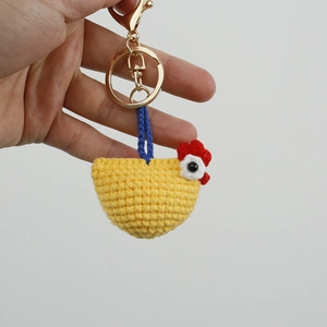 Handmade crochet yellow chicken keychain with red comb and blue lanyard on white background