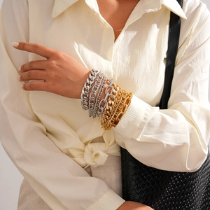 Detail shot of multi-layered gold and silver chunky Cuban chain bracelets on model's wrist