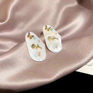 Boucles d'oreilles ovales en nacre avec fleur dorée, papillon et cristaux de luxe