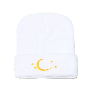 Détail du bonnet en tricot blanc avec broderie de lune et d'étoile jaune