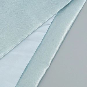 Gros plan sur un tissu satiné bleu clair avec texture soie et reflets métalliques chics