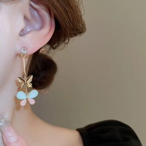 Detail of elegant butterfly dangle earrings with resin wings and zircon stone on model