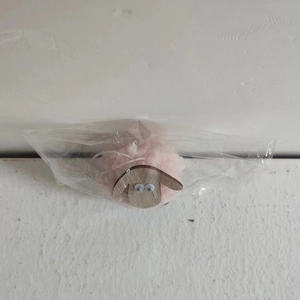 Detailed close-up of a pink felt sheep ornament packaged in a clear plastic bag