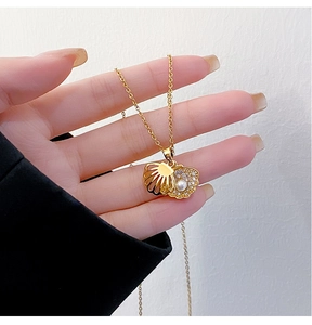 Close-up of golden shell necklace with micro-pave zircons and lustrous pearl inlay