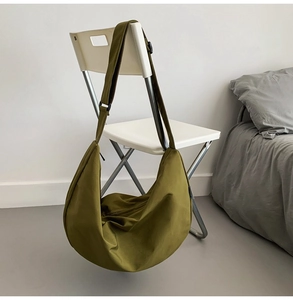 Detail of the olive green crescent bag with wide adjustable strap on a chair