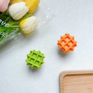 Dettaglio del supporto per telefono a forma di waffle verde e arancione su bianco