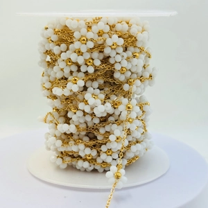 Dettaglio di perline a fiori bianchi e catena d'oro in rotolo per gioielli fai da te