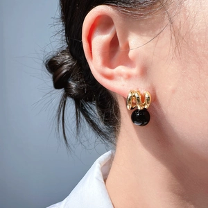 Vintage black onyx drop earrings with golden wave metal layers worn by a model