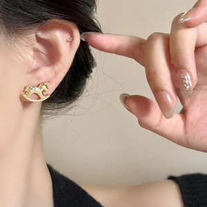 Detail of 18k gold plated rocking horse charm earring worn by a model