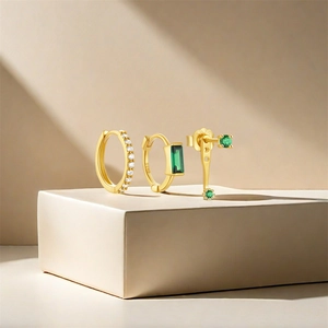 Macro detail of S925 sterling silver gold-plated earring set with green gems and diamonds