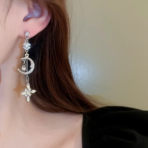 Detailed view of silver star and moon drop earrings with crystal tassels on female model