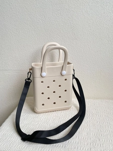 Detail view of beige EVA tote bag featuring perforated holes and black woven shoulder strap