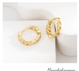 Macro detail of gold heart earrings with micro-inlaid zirconium and 14k gold finish
