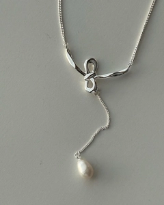 Detail of sterling silver bow necklace featuring a natural white freshwater pearl pendant