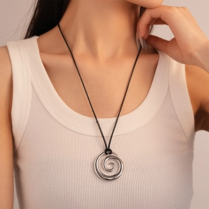 Detail of silver spiral pendant necklace worn on a ribbed top for modern styling