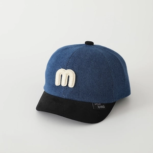 Dettaglio cappellino in denim blu con ricamo M bianco 3D e visiera corta nera strutturata