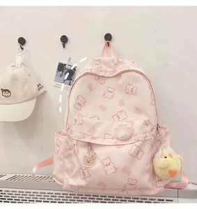 Close-up of pink bear print backpack with cute plush chicken and acrylic bear charms
