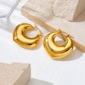 Polished gold teardrop hollow earrings in stainless steel on a beige stone display
