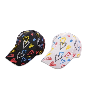 Set of black and white baseball caps with colorful hand-drawn heart patterns on cotton fabric