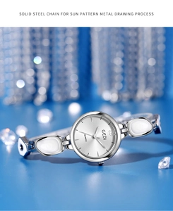 Silver bracelet watch with sunray dial and crystal accents on reflective blue surface