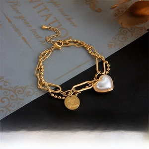 Macro detail of gold double-layer chain bracelet with pearl heart and Love Dream charm