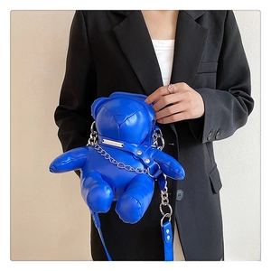 Blue bear-shaped crossbody bag shown on a model with a silver chain and metal badge